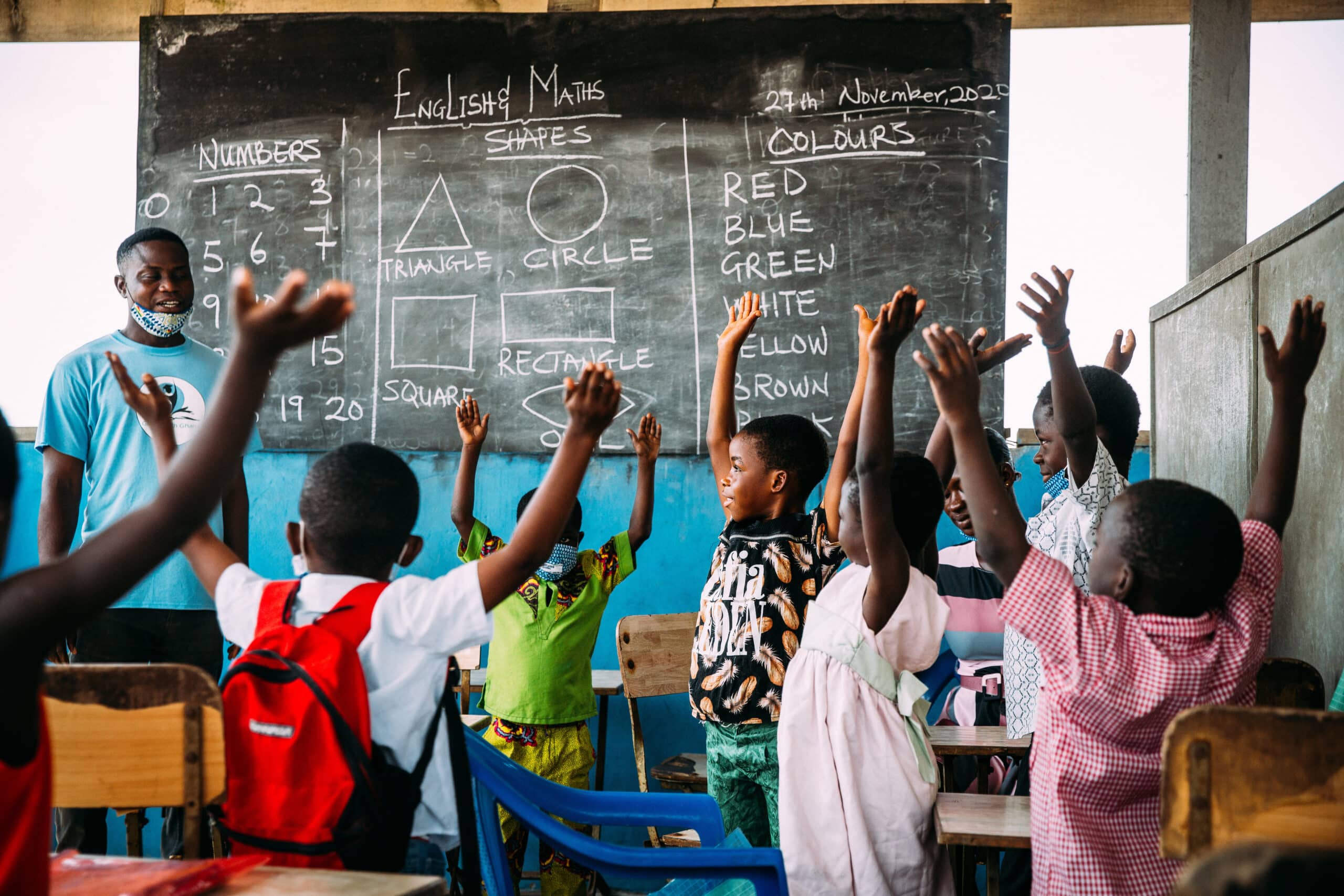 Skolebarn i Ghana rekker opp hendene sine