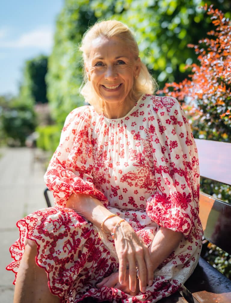 Advokat Marianne Blystad sitter på en benk og smiler. Foto: Schibsted