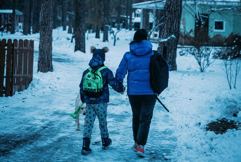 En voksen leier et barn, de har begge rygen til. Det er vinter og i forgrunnen skimtes barnebyen i Brovary. Foto: Alea Horst