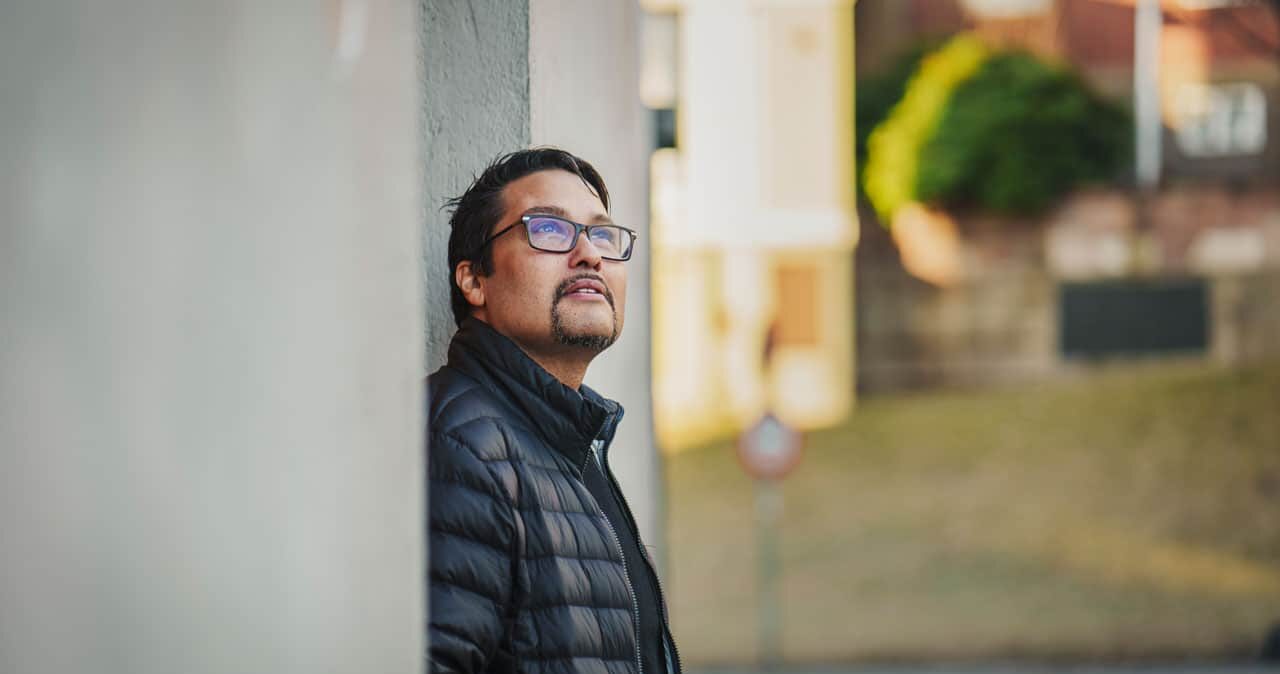 Daniel Siraj, konserndirektør i OBOS, står lent inntil en vegg. Han har mørkt kort hår, skjegg, briller og blå dunjakke. Foto: Hampus Lundgren