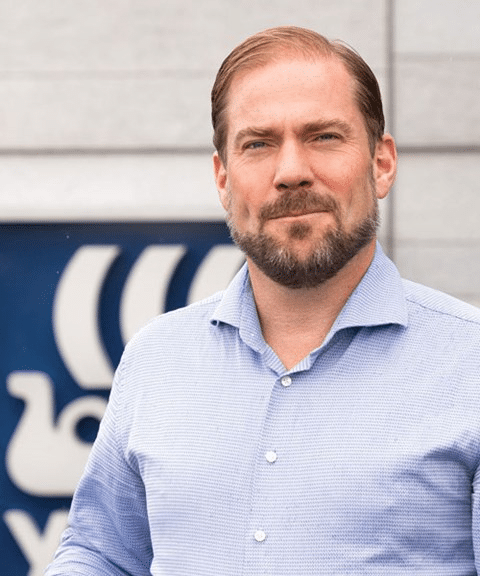 Aleksander Jankov, sikkerhetsansvarlig i Yara internasjonalt. Han har mørkt hår og skjegg, og har på seg en lyseblåskjorte. I bakgrunnne er det et skilt med Yaras logo. Foto: Claire Ines Coriat
