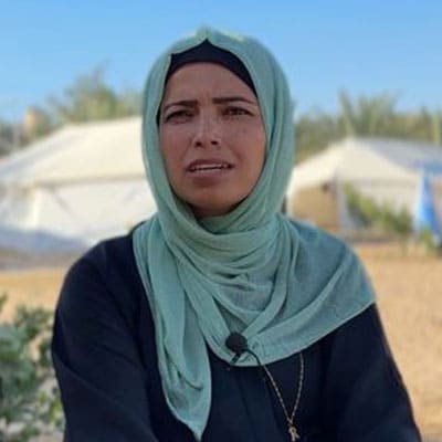 Reem Alreqeb, programansvarlig SOS-barnebyer Gaza. hun står foran noen telt og har på seg lys turkis hijab og svart kjole. Foto SOS-barnebyer Palestina