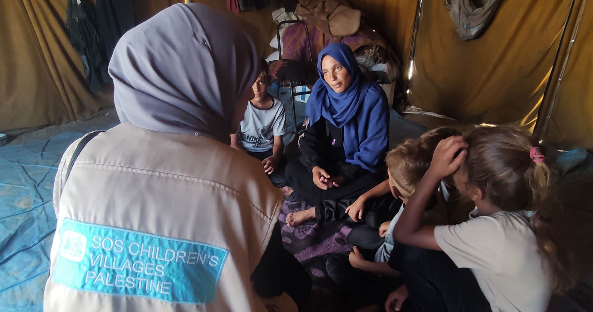 Gaza: En sosialarbeider fra SOS-barnebyer snakker med en familie i teltleiren. Foto: SOS-barnebyer Palestina