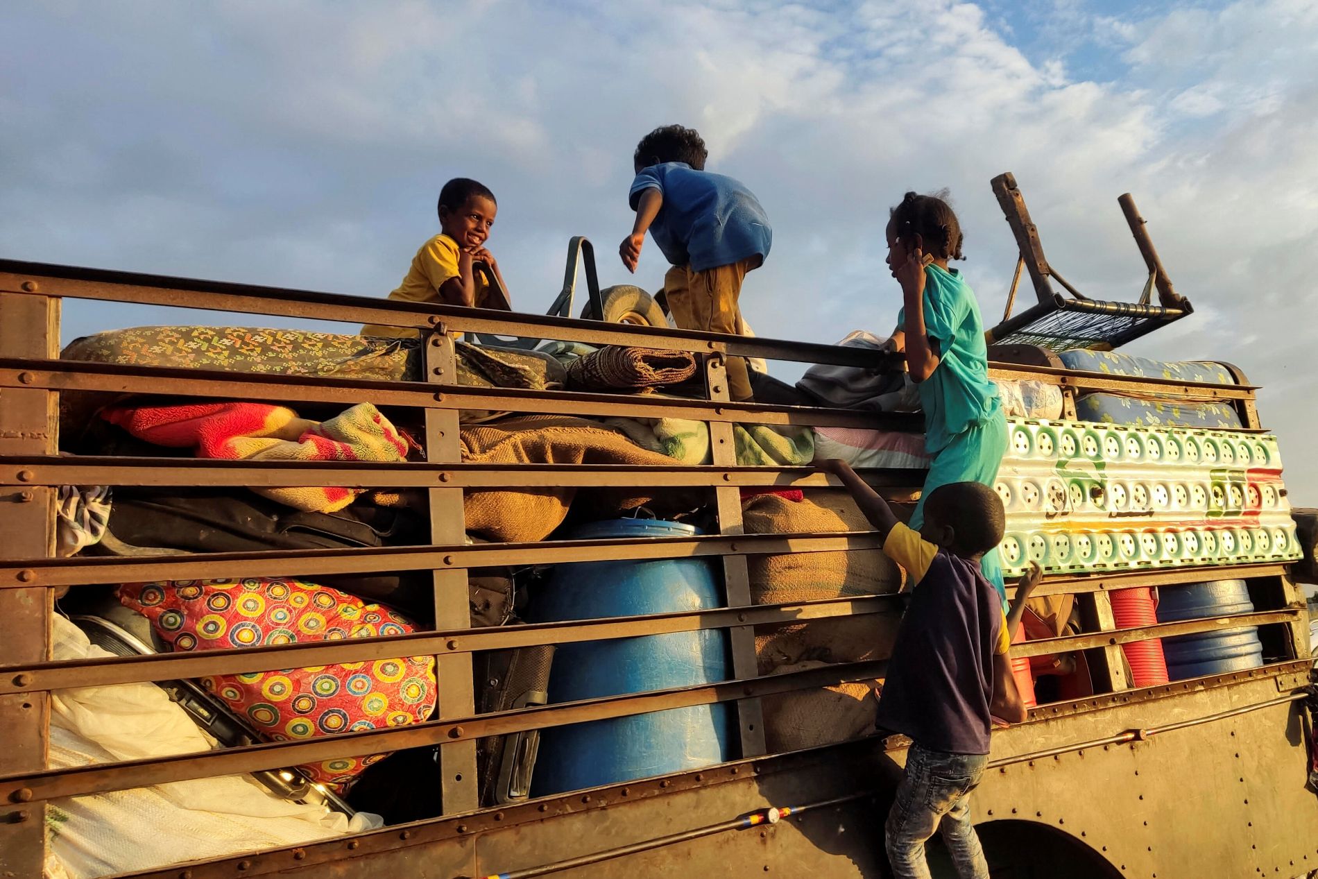 Barn på flukt i Sudan, klatrer opp på lastebil. Foto: AFP